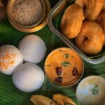 Delicious South Indian breakfast with idli, vada, chutney, and coffee on banana leaf.